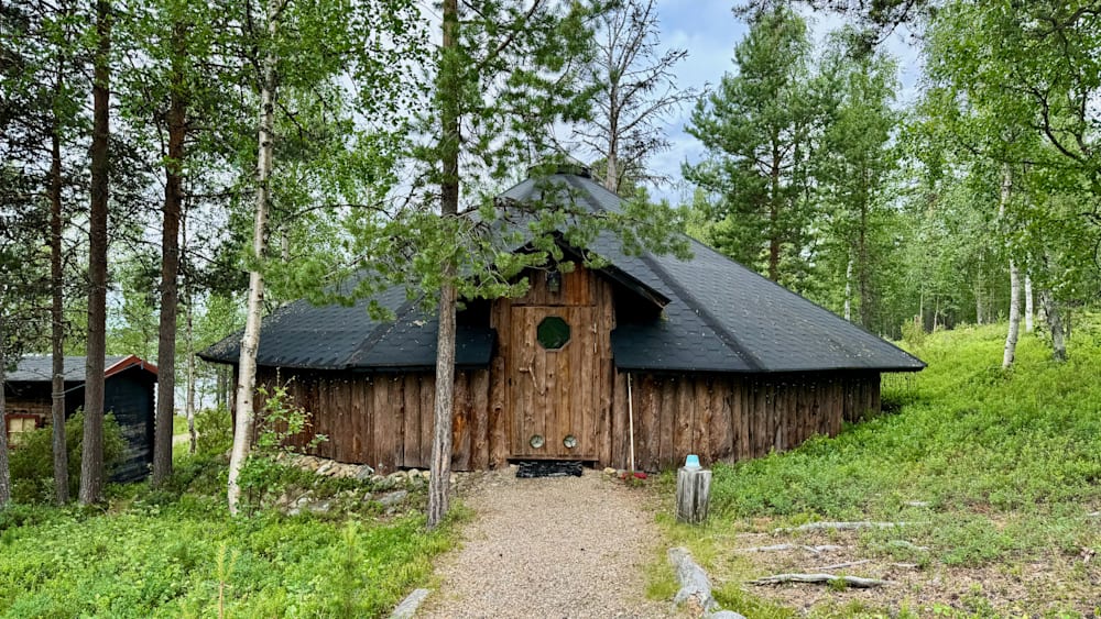 A log cabin with a gravel driveway leading to it.