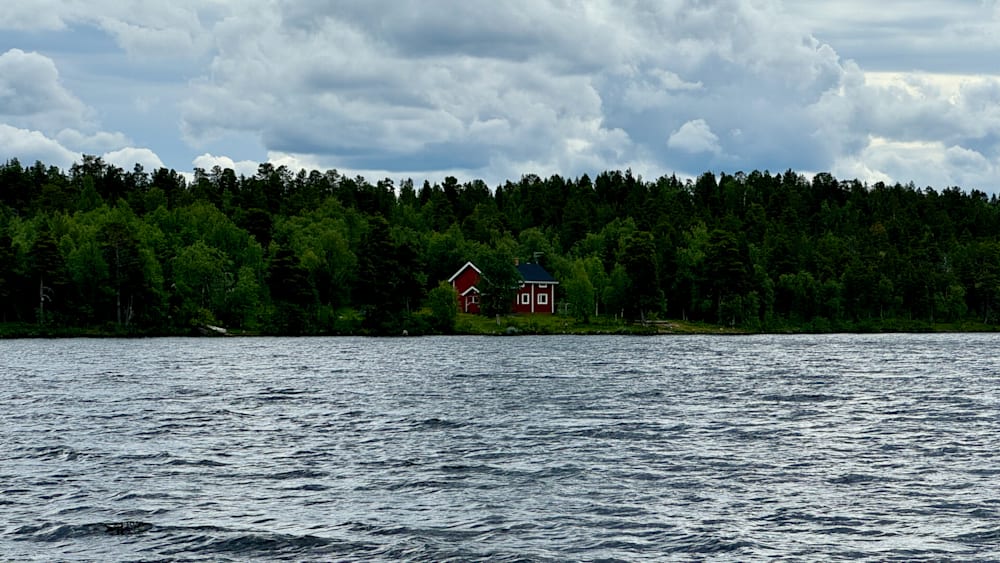 A house on a lake with a cloudy sky in the background.