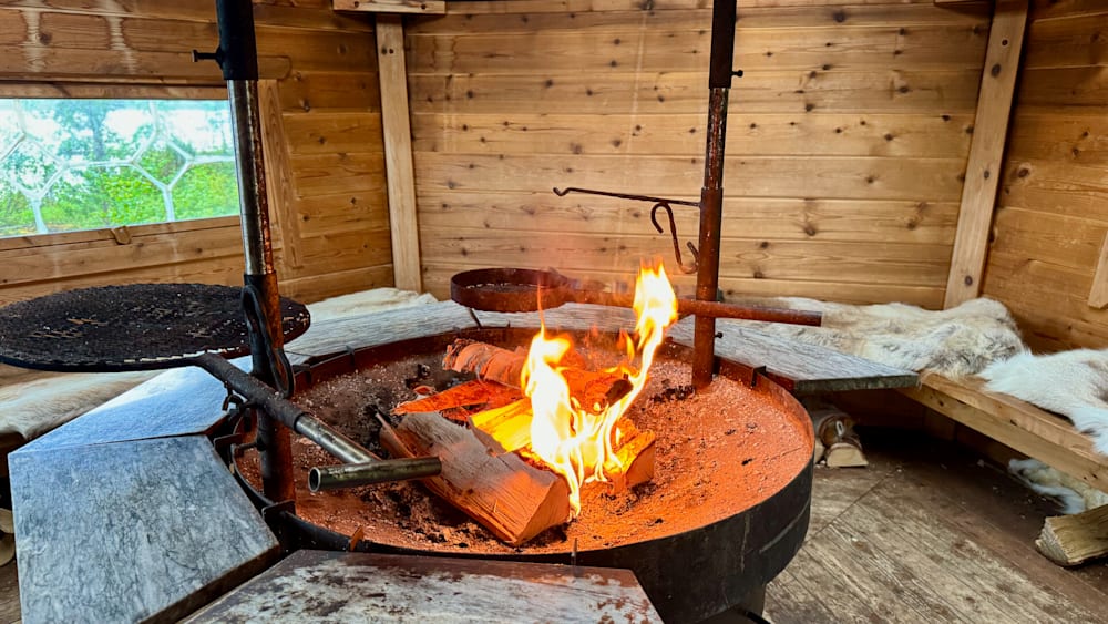 A fire is burning brightly in a pit, and a large log is in the pit as well.