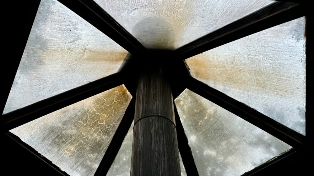 A view of a pole and its cracks from under a glass roof.