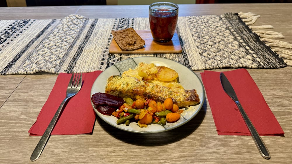 A plate of food with a fork and knife on a table with a glass of wine.