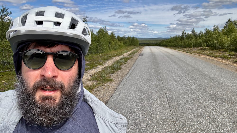 A man wearing a helmet is taking a picture of himself in the mirror.