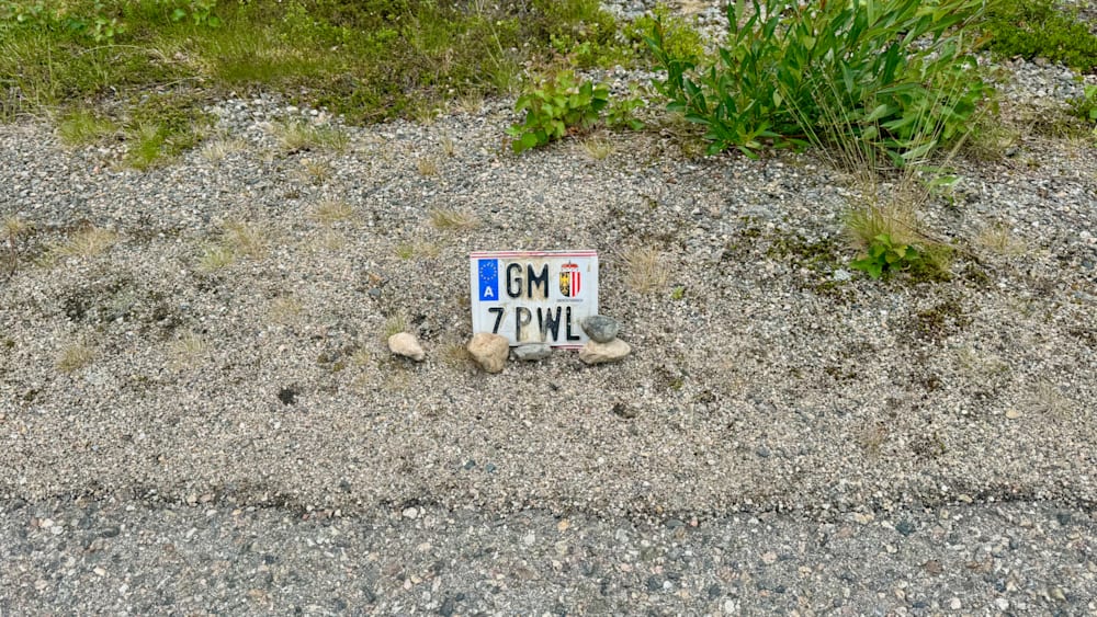 license plate with 7 pl on it is sitting on some rocks.