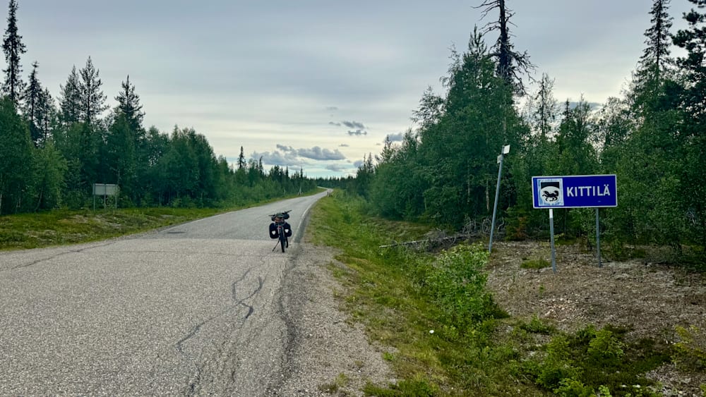 A person with a bike on the side of a road that says "bird" on it.