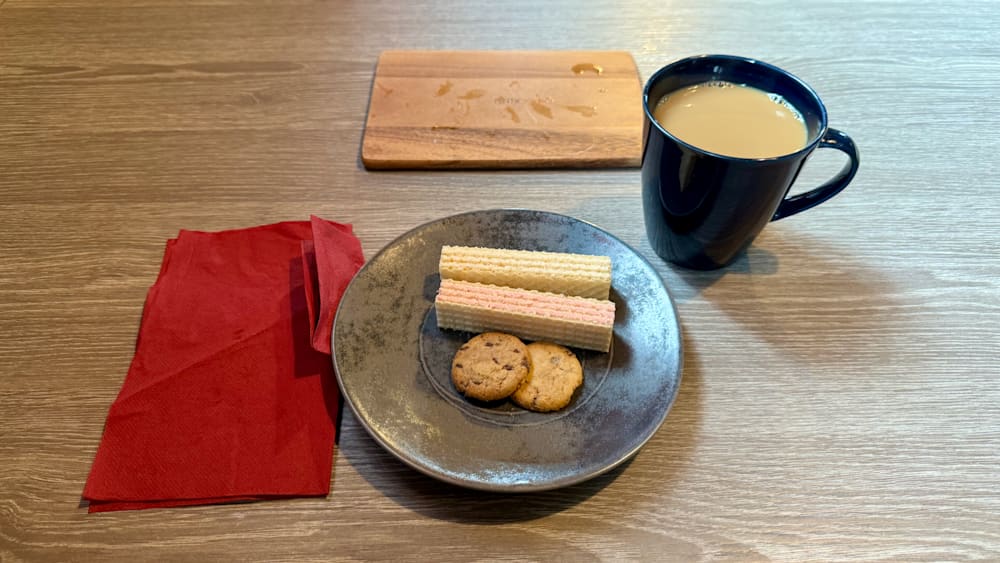 A couple of cookies are sitting on a plate next to a cup of coffee.