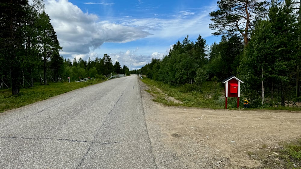 A road with no cars or people on it and a red mailbox on the side.