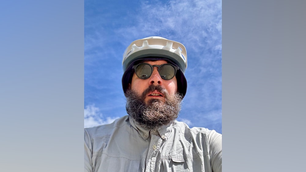 A man with a beard and a helmet in front of him.