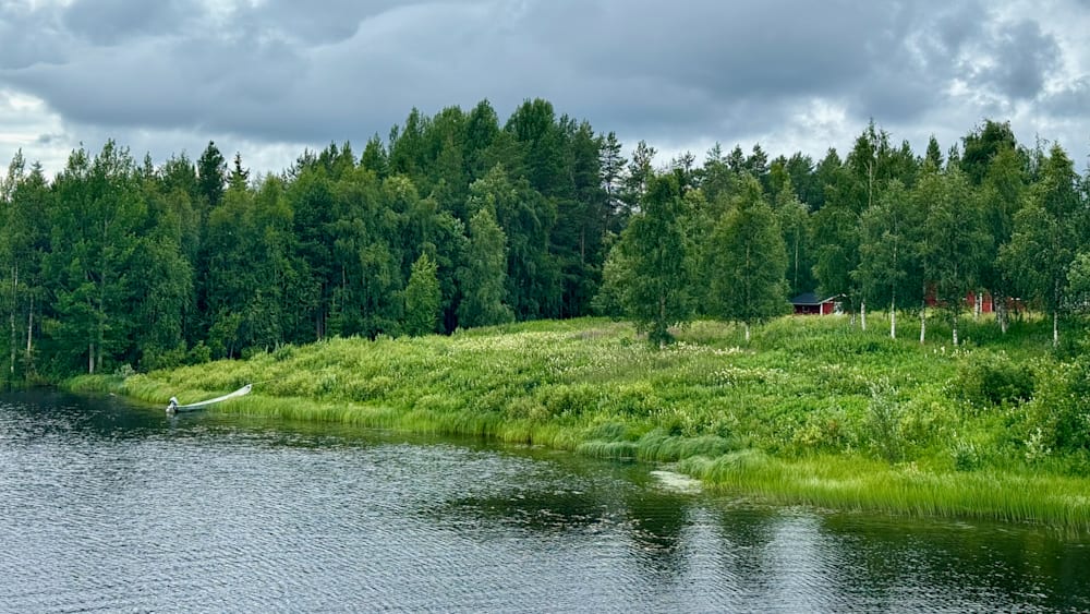 A house is on the shore of a lake surrounded by trees.