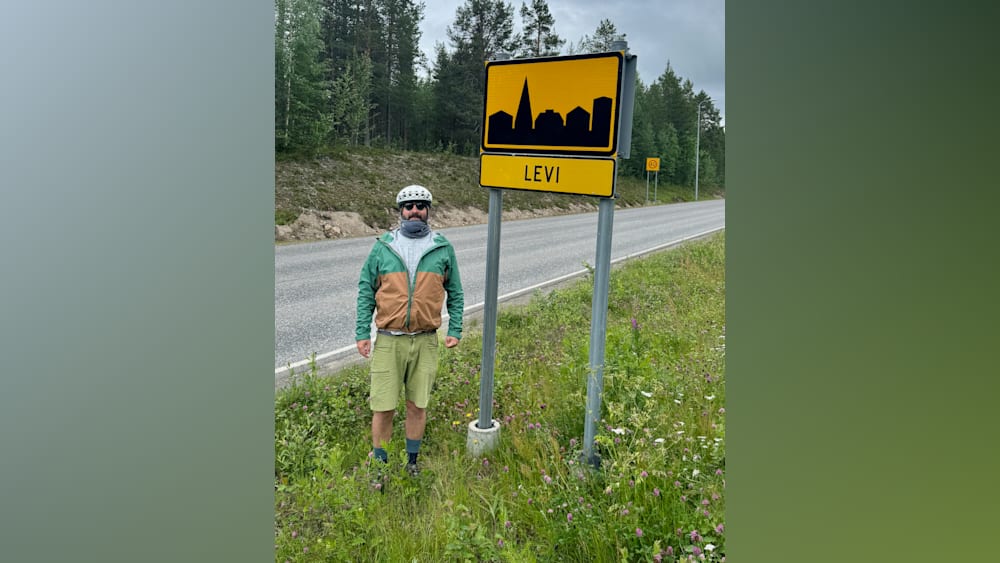 A man stands in front of a sign that says "LVI" on it.