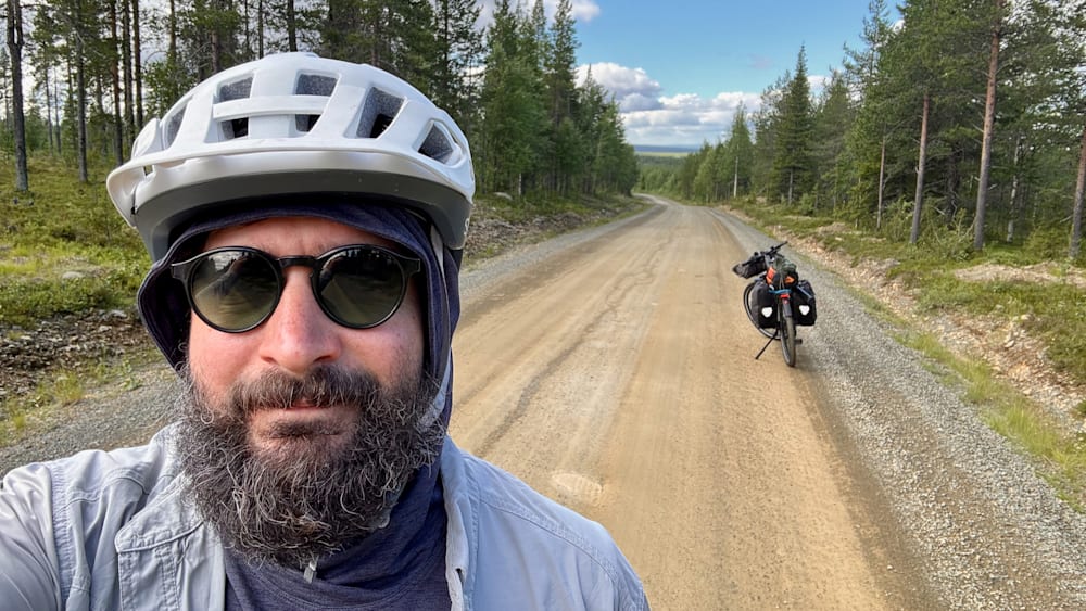 A man wearing a white helmet takes a picture of himself in the mirror.