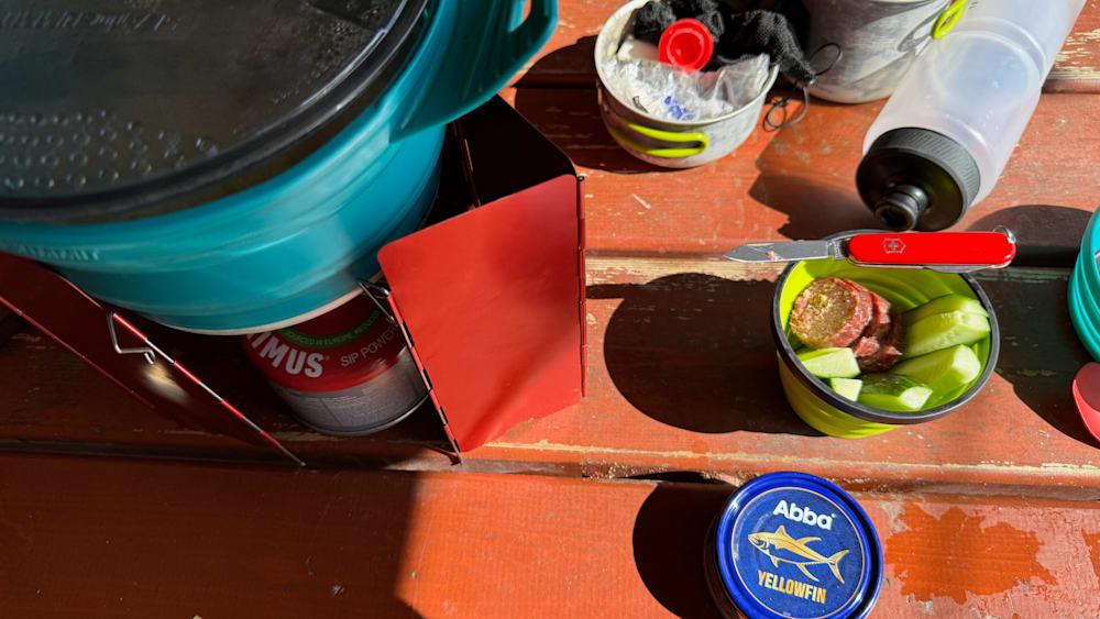 A container of "abba" fish sauce is on a wooden table along with other food items.