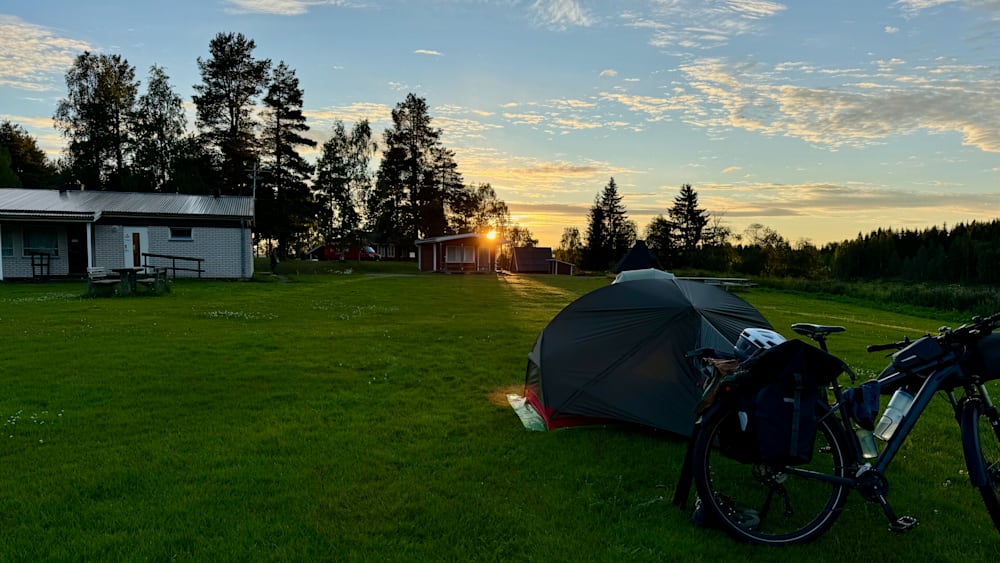 A tent is set up on a grassy area with a bike nearby.