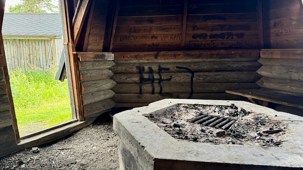 A concrete structure with a fire pit in it and graffiti on the wall with the letters "HA" written on it.