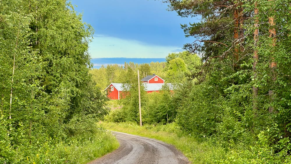 A red barn and two other buildings are in the background of a road.