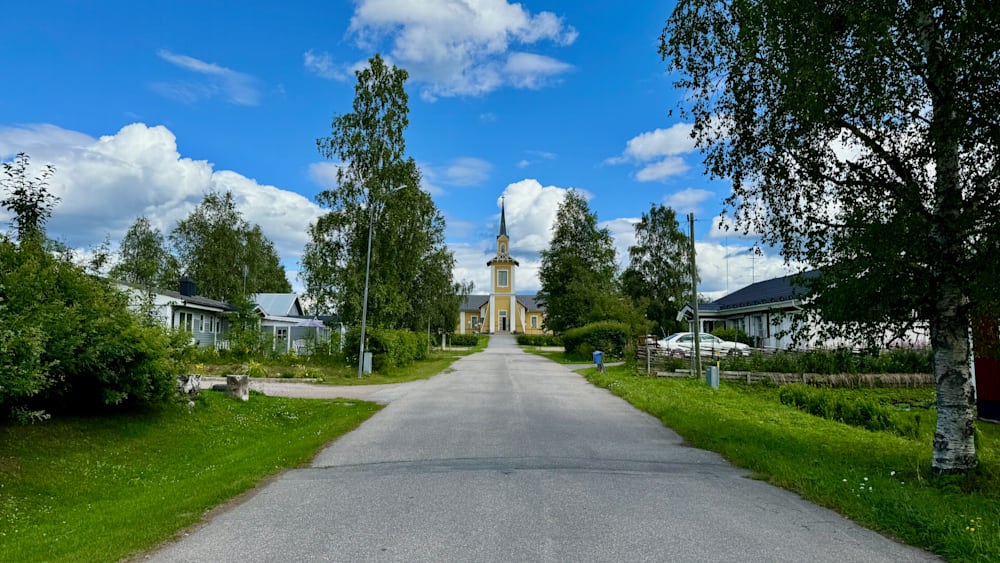 A church with a yellow steeple and a small cross on top.