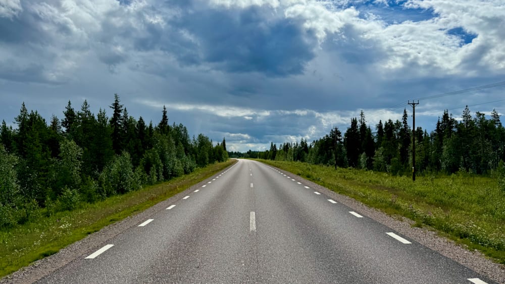 An empty road is shown with a large cloud in the background.