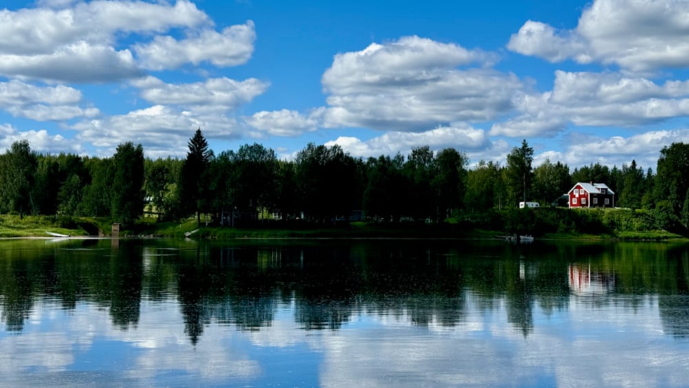 A lake is reflected in the sky and trees, creating a serene scene.