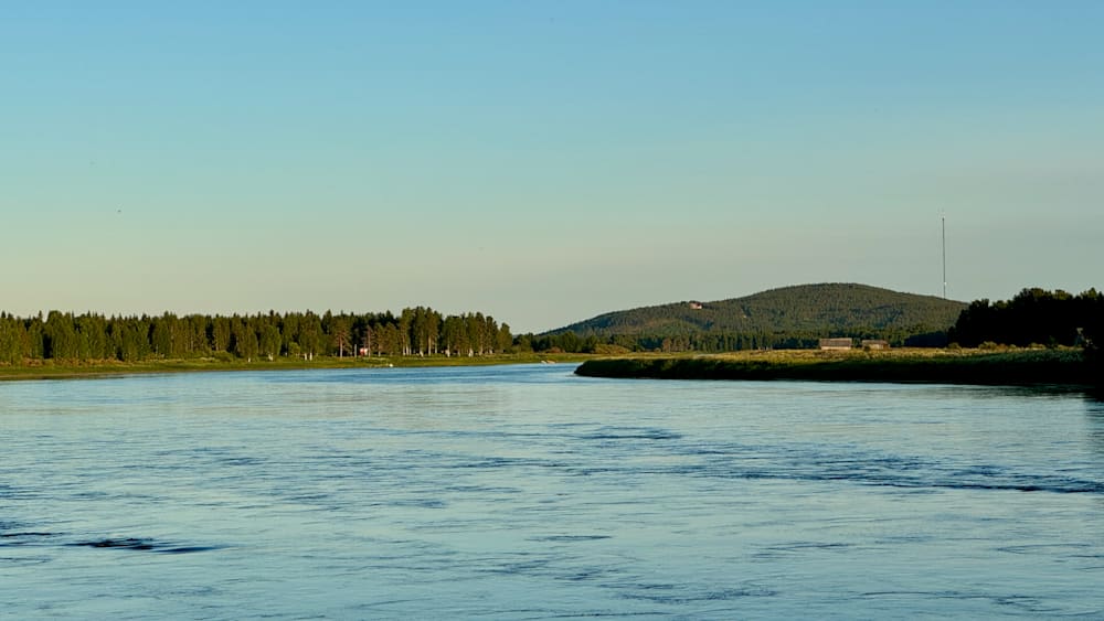 A river with trees on its banks and a house near the water.