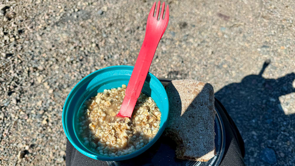 A bowl of oatmeal with a red plastic spoon in it.
