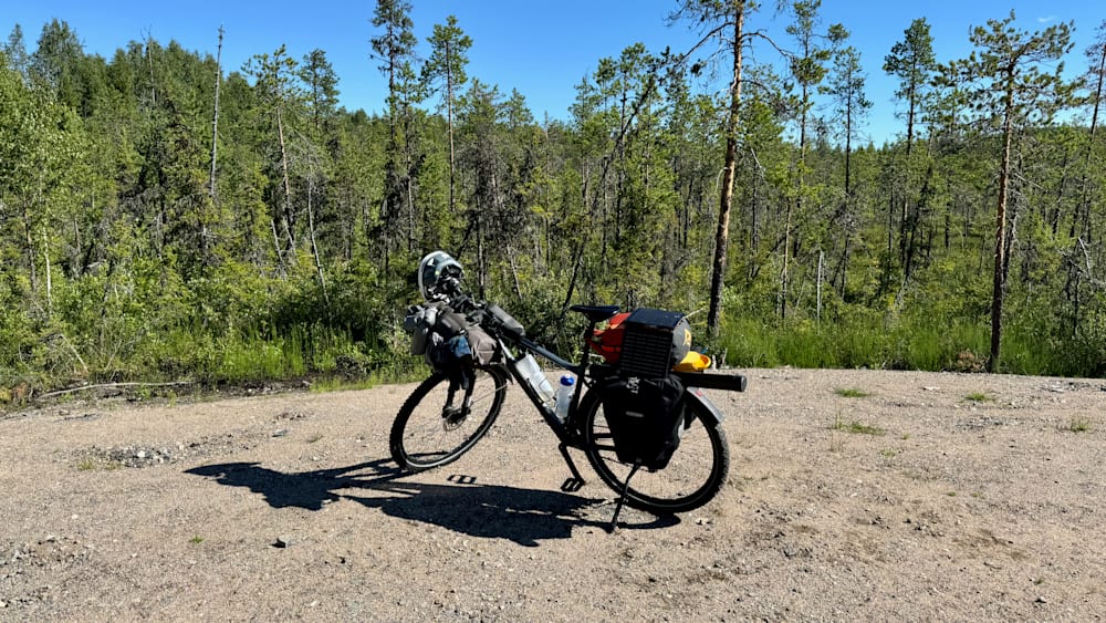 A mountain bike is sitting on a dirt path with a backpack on it.