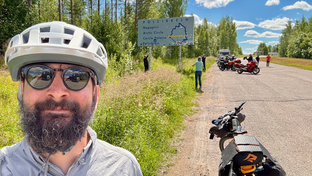 A man wearing a helmet takes a picture of himself with a sign in the background.