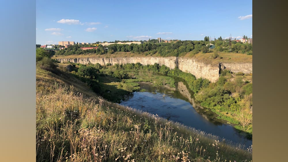 A river flows through a field and pastures before it empties into a lake.