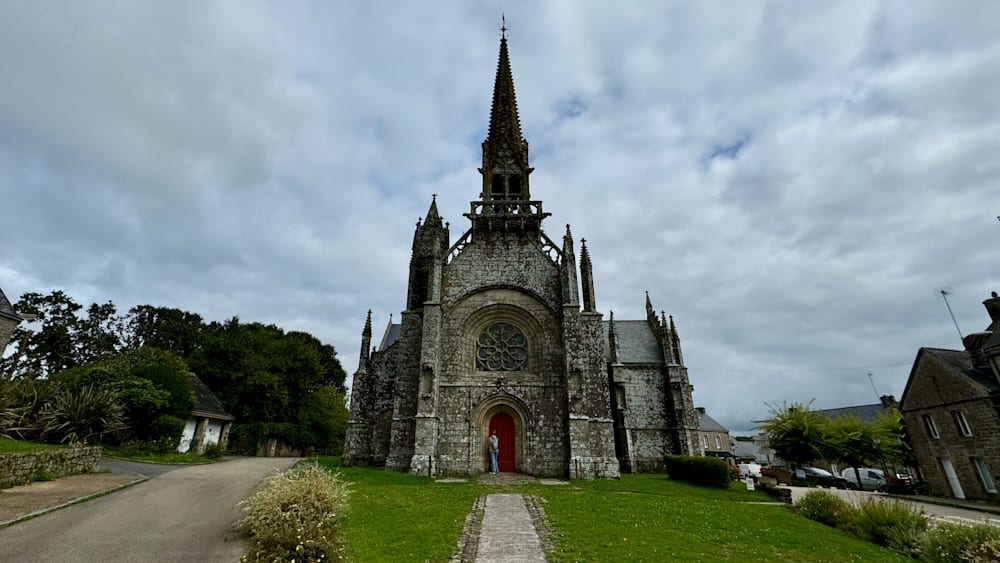 A woman standing in front of a church with a red door.