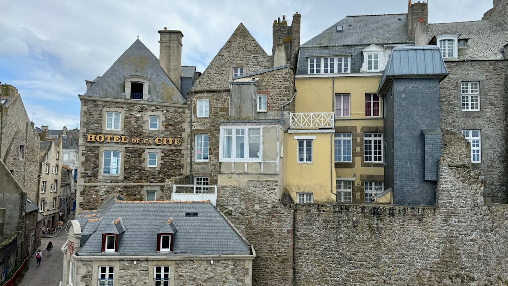 A row of brick buildings that look old fashioned and have a hotel on the ground floor.