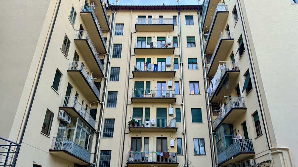 A balcony on the side of a large building with clothes drying on it.