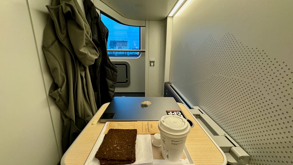 A cup of coffee sits on a small table next to a laptop.