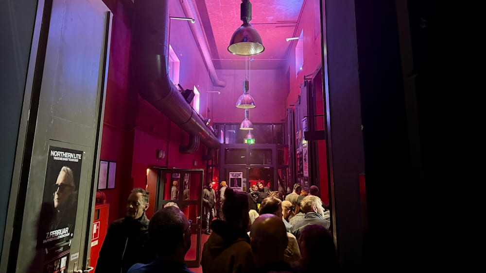 A large group of people are standing in a room with neon lights.