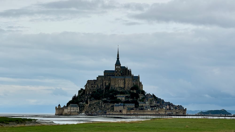 A large castle is in the distance with a bridge leading to it.