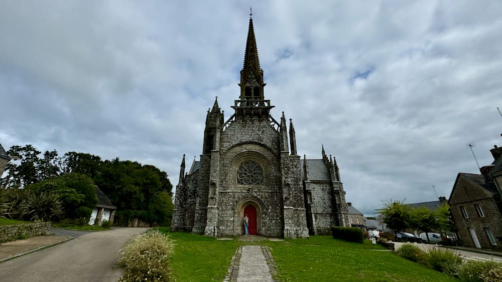 A woman standing in front of a church with a red door.