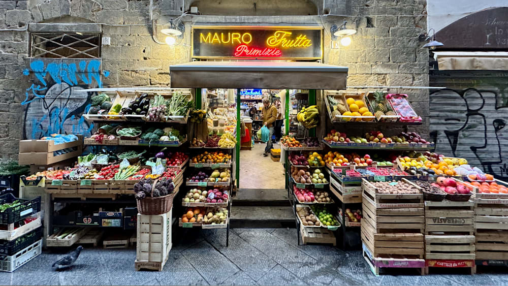 A store that sells fruit has a bright neon sign that says Mauro Primières.