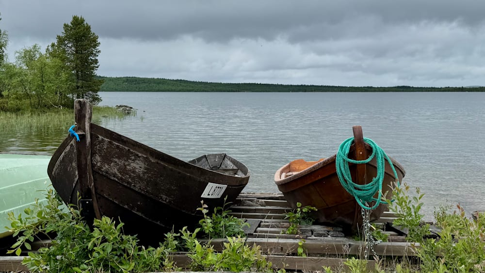 A row of boats are tied up at the dock on a cloudy day.