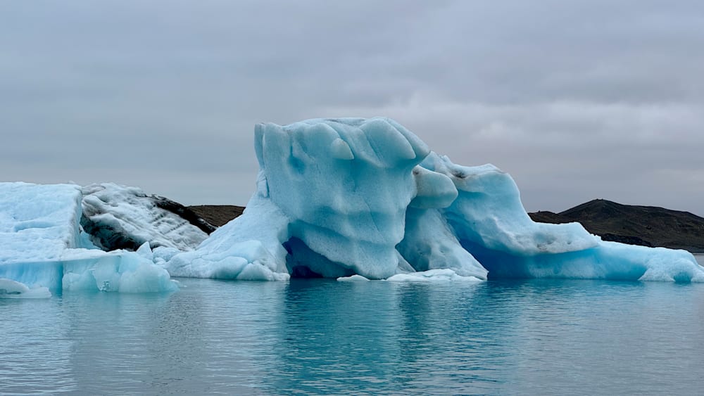 A large block of ice is resting in the ocean surrounded by water.