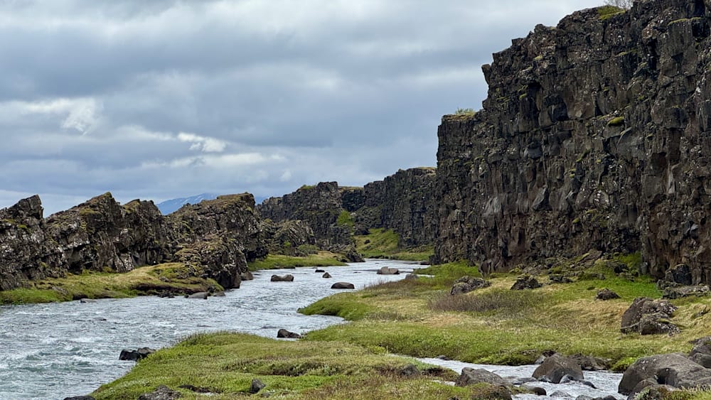 A river runs through a rocky landscape with huge cliffs on either side.