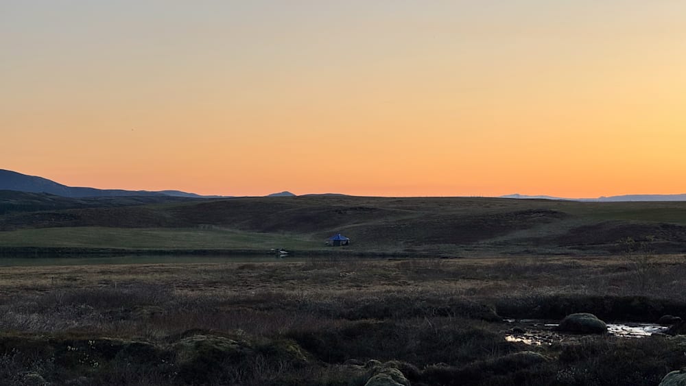 A blue tent can be seen in the distance on a hillside.