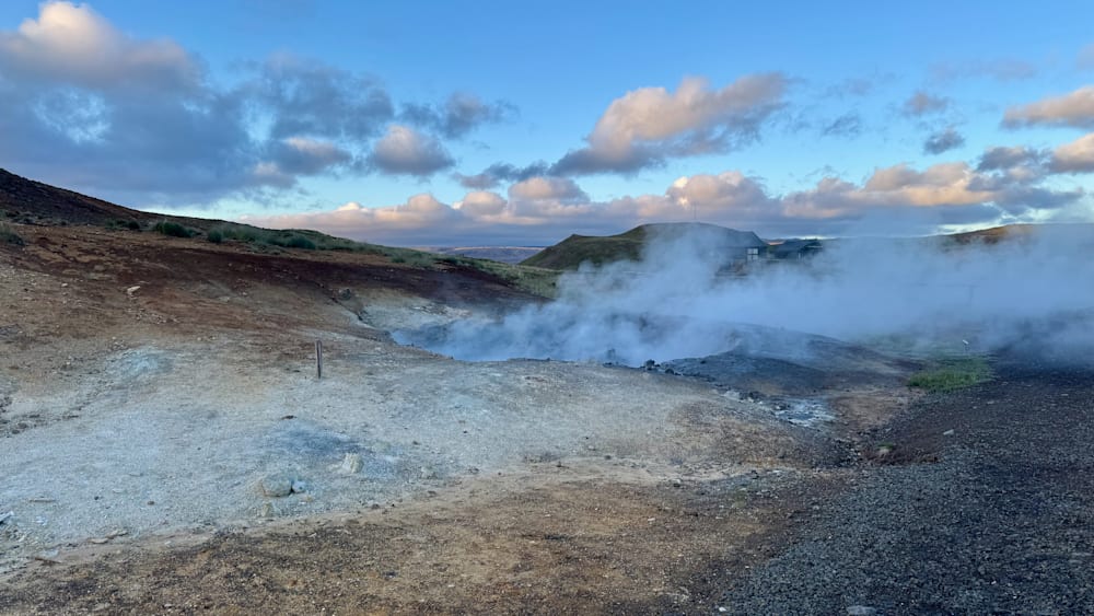 A large open pit with steam coming out of it.
