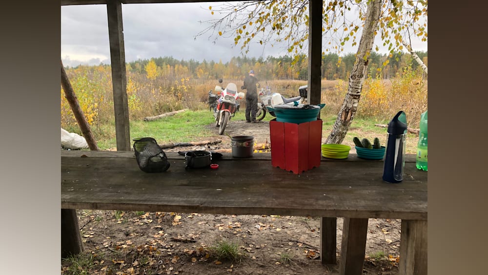 A table with a camping stove and some vegetables on it.