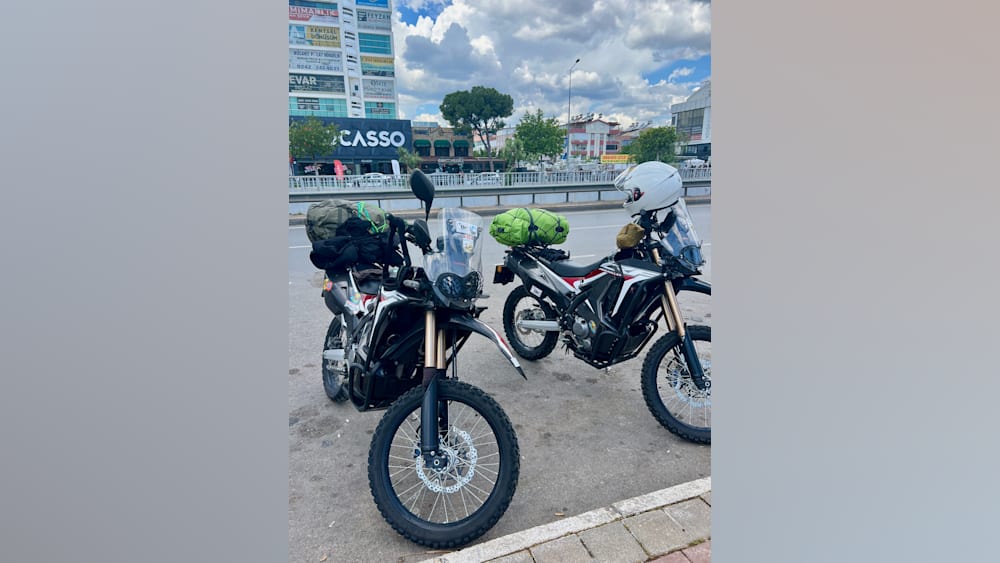 Two motorcycles with helmets on them parked next to a building.