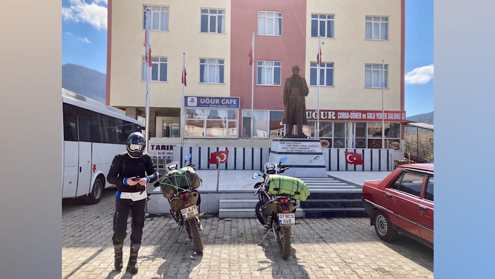 A man standing next to his motorcycle on the street.