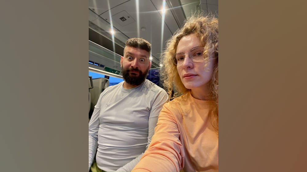 A man and woman wearing the same shirt are looking at the camera.