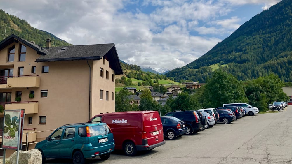 Several cars are parked, including a red Miele van.