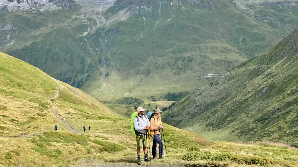 A man and woman standing on a mountain with backpacks.