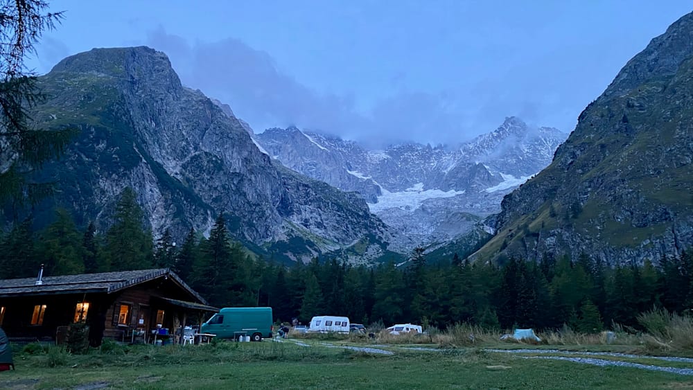 A group of campers are parked in front of a large mountain range.