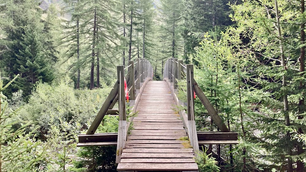 A wooden bridge over a river is being photographed from the side.