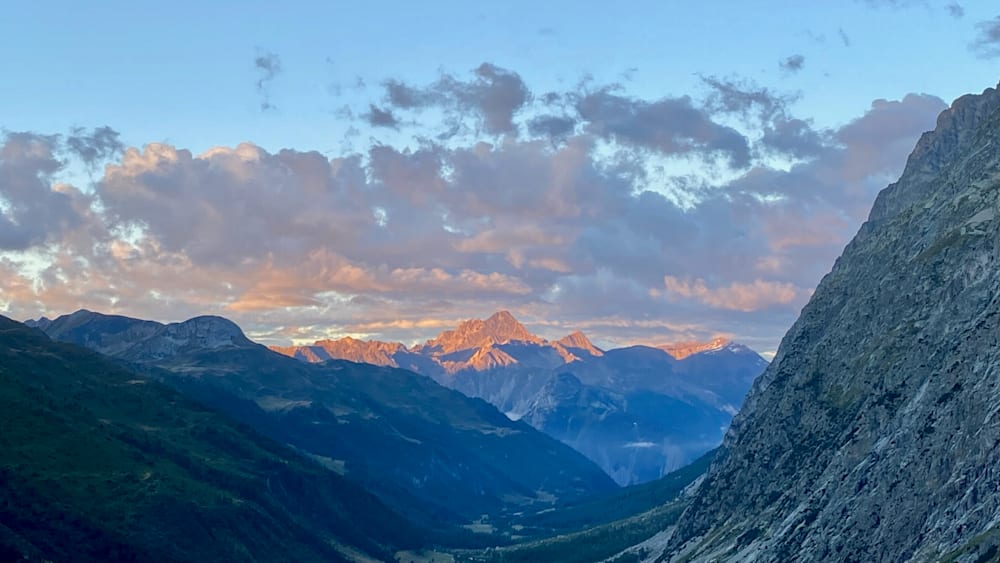 A mountain with a sunset behind it on the horizon.