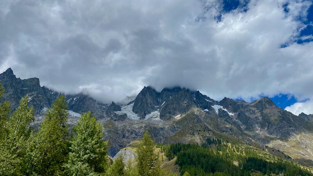 A foggy mountain peak with snow on its side.