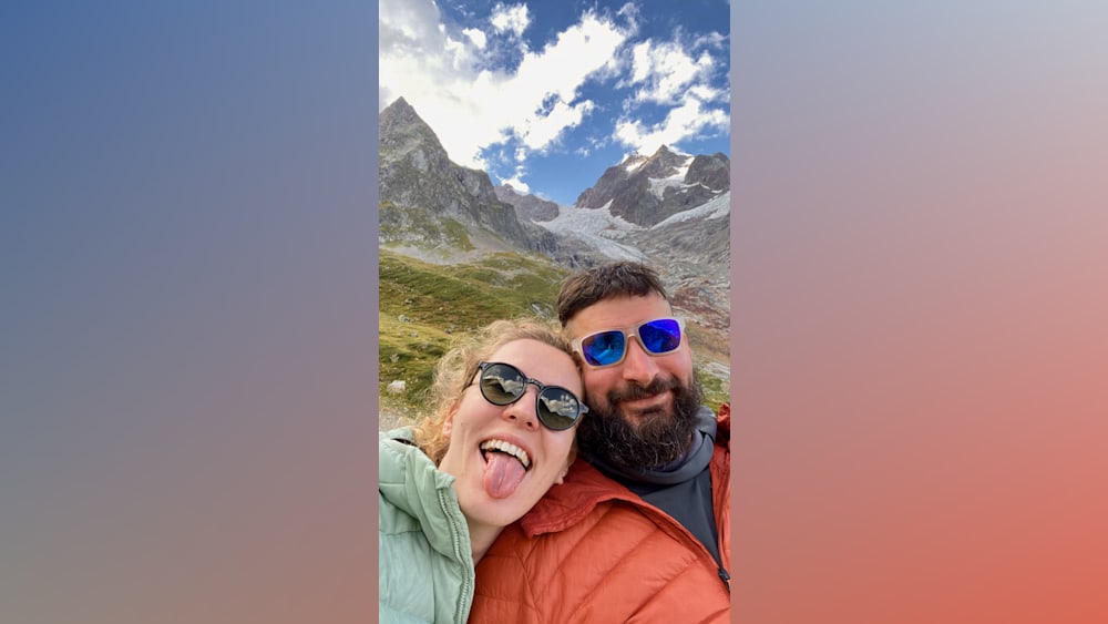 A woman with her tongue out taking a picture of a man with a beard.